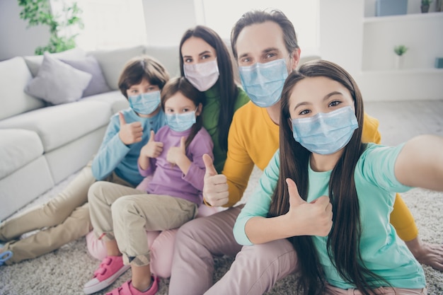 Autorretrato de uma bela família grande, atraente, cheia, crianças pré-adolescentes mãe pai mostrando thumbup passando tempo feriado dia mers cov medidas preventivas para evitar infecção na casa apartamento sala de estar