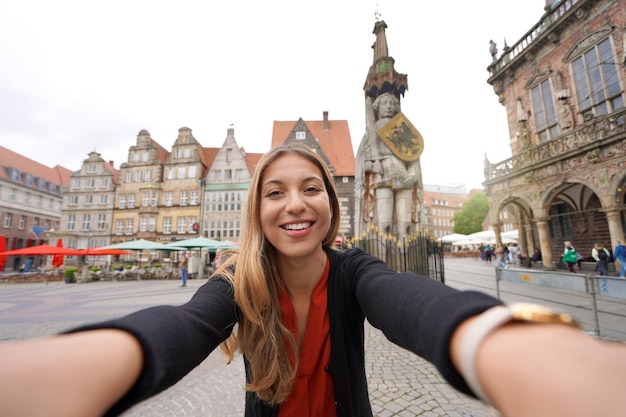 Foto autorretrato de mujer joven en la plaza del mercado de bremen con estatua de roland alemania