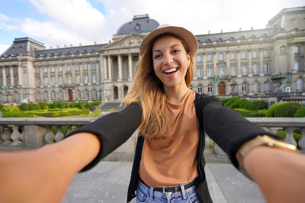 Autorretrato de mujer viajera feliz al atardecer con el Palacio Real de Bruselas en el fondo Bélgica