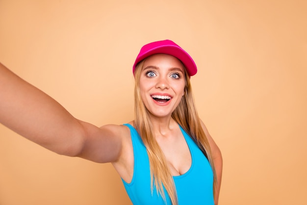 Autorretrato de niña linda con gorra rosa brillante aislada en beige