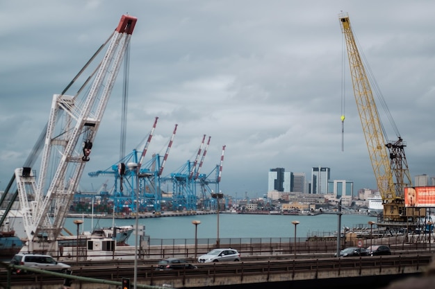 Autos auf der Brücke über den Fluss gegen Kräne im Hafen von Genua