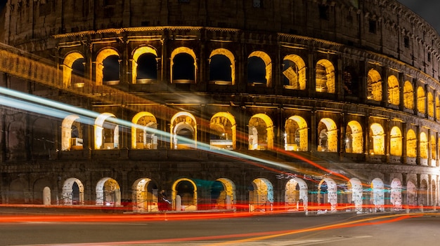 Autos beleuchten Wege in der Nähe des Kolosseums in der Abend- oder Nachtzeit Berühmtes Wahrzeichen Roms Italien