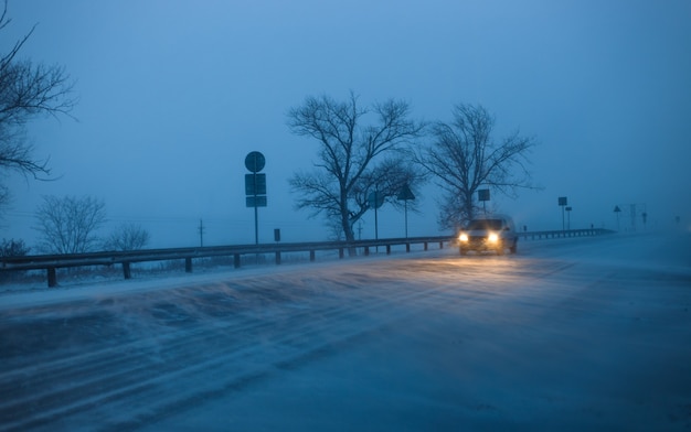 Autos fahren abends während eines Schneesturms auf der Autobahn.