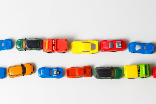 Los autos de juguete multicolores de plástico están alineados en blanco