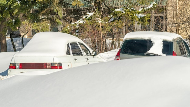 Autos parken auf einem Parkplatz mit Schnee auf dem Dach und eines von ihnen hat ein weißes Dach.