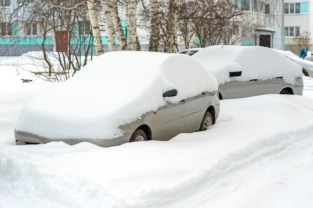 Autos unter dem Schnee auf einem Parkplatz in der Nähe eines Mehrfamilienhauses