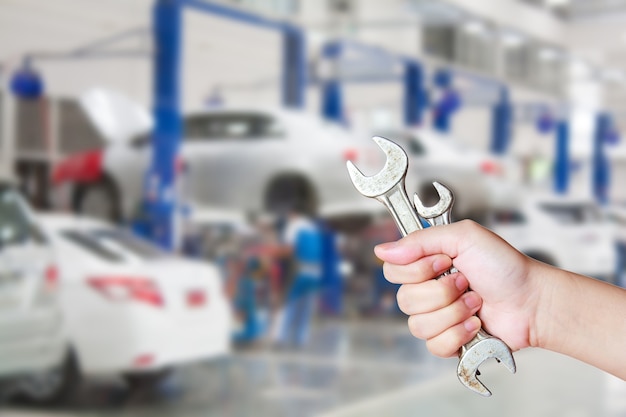 Autoservice-Center und eine Arbeiterhand mit einem Schraubenschlüssel