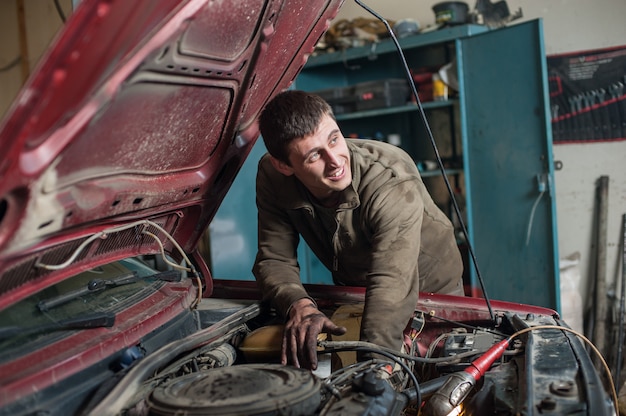 Autoservice-Mechaniker, der in einem Auto unter der Haube arbeitet