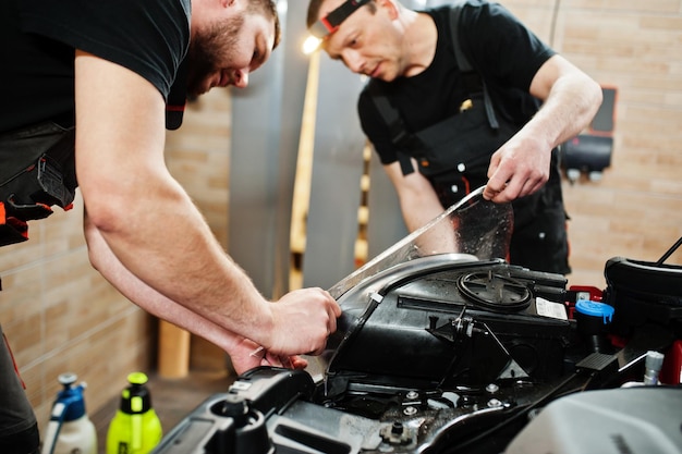 Autoservice-Mitarbeiter legten in der Fahrzeugwerkstatt eine rote Karosserie mit Anti-Kies-Folie an Autoschutz mit Spezialfolien