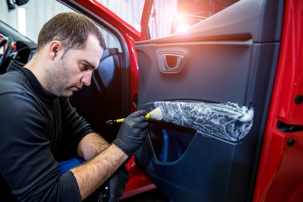 Foto autoservice-mitarbeiter reinigt den innenraum mit spezialbürste