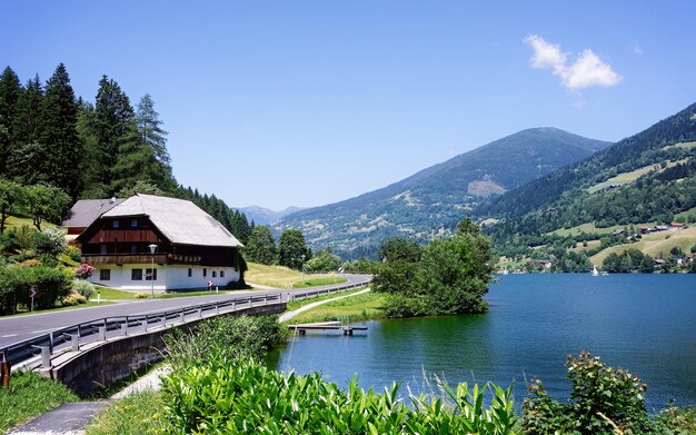 Foto autostraße am see feld am see von kärnten von österreich. landschaft mit autobahn für fahrten und fahrten am teich und blauem himmel im frühling oder sommer. landschaft in den grünen alpen europas.