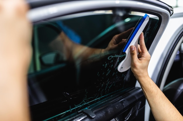 Autotönung - Arbeiter, die Tönungsfolie auf Autofenster aufbringen.