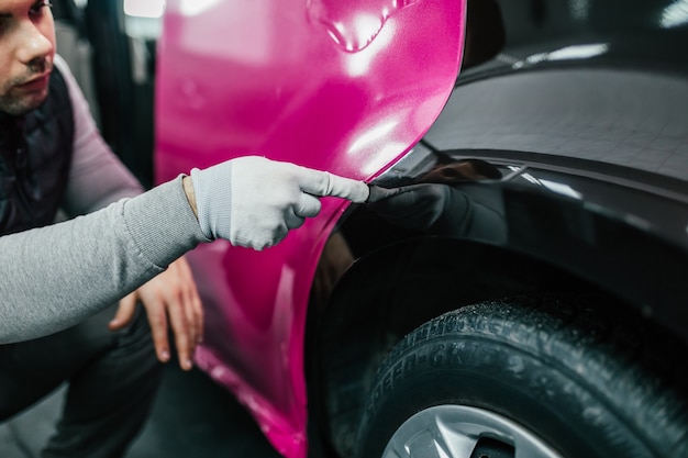 Autoverpackungsspezialist, der Vinylfolie oder Film auf das Auto legt Selektiver Fokus.