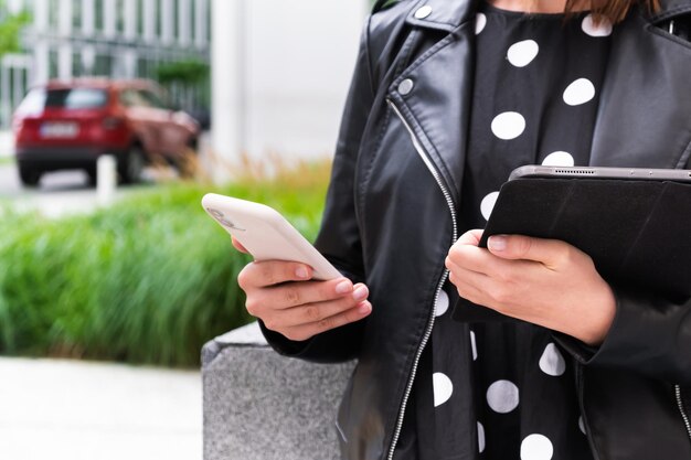 Autoversicherungsagent, der den Hintergrund eines roten Autos anruft Fröhliche junge Frau, die mit Handy und Tablet auf der Straße steht