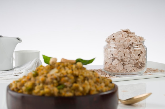 Aval upma ou poha upma ou kanda poha upma, item de café da manhã indiano saudável que é muito saboroso e fácil de cozinhar e é organizado em uma tigela de madeira com fundo texturizado branco, foco seletivo.