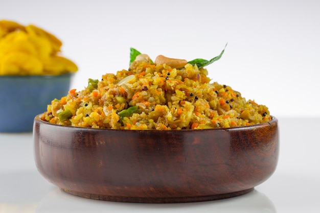 Aval upma ou poha upma ou kanda poha upma, item de café da manhã indiano saudável que é muito saboroso e fácil de cozinhar e é organizado em uma tigela de madeira com fundo texturizado branco.