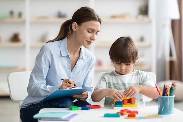 Avaliação da psicóloga profissional de desenvolvimento mental infantil assistindo garotinho jogando