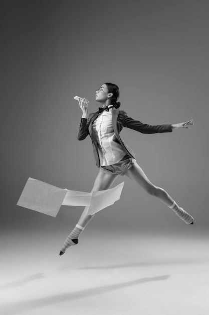 Ave volando. Joven mujer de moda y elegante con chaqueta y calcetines trabajando desde casa. Moda durante el aislamiento por causa de la pandemia de coronavirus. Mitad de estilo comercial y mitad hogareño. En blanco y negro.