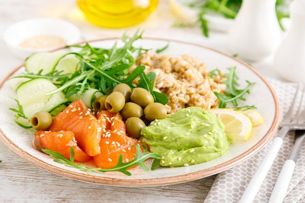 Aveia com guacamole de abacate com salmão salgado e salada de vegetais frescos de rúcula, pepino e azeitonas Café da manhã