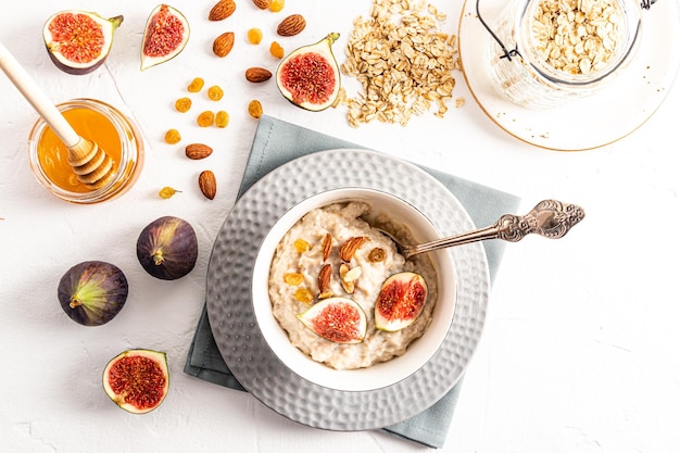 Aveia de café da manhã saudável e saudável com frutas secas e figos em uma tigela sobre uma mesa branca visão superior de nutrição equilibrada