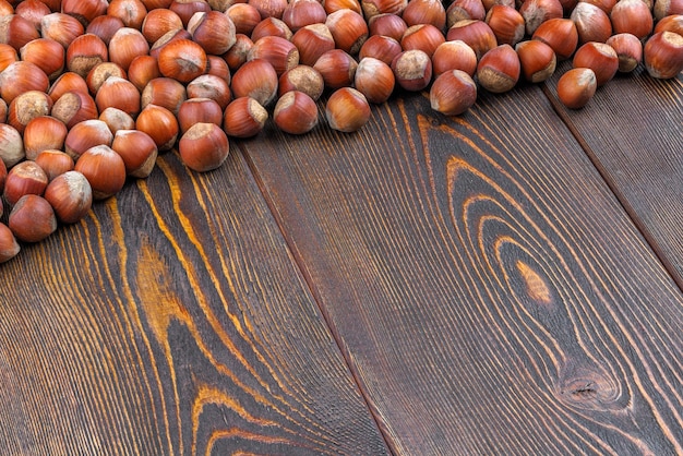 Avelãs com cascas colocadas na superfície da mesa de madeira marrom