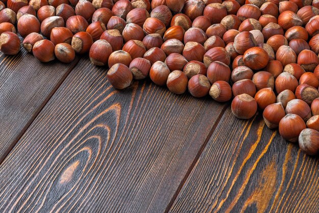 Avelãs com cascas colocadas na superfície da mesa de madeira marrom