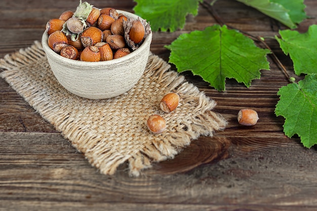 Avelãs em um fundo de madeira com folhas verdes. contém vitaminas e minerais benéficos.