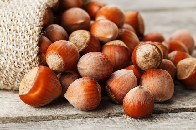 Avelãs em uma capa, derramado de um saco de estopa em uma mesa de madeira cinza