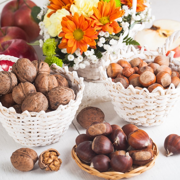 Avelãs, nozes e castanhas com maçãs e buquê outonal