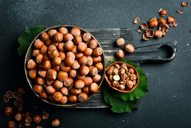 Foto las avellanas en conchas esparcidas de un saco de arpillera vintage sobre un fondo oscuro algunas están descascaradas y otras están agrietadas un rompedor de nueces de metal está allí para abrir las nueces