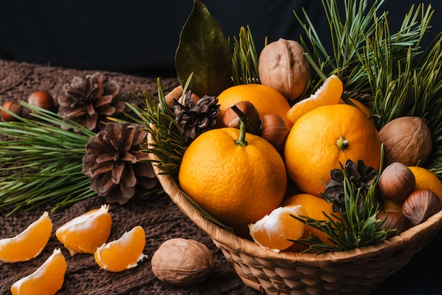 Avellanas, nueces y mandarinas decoradas con ramas navideñas y piñas.