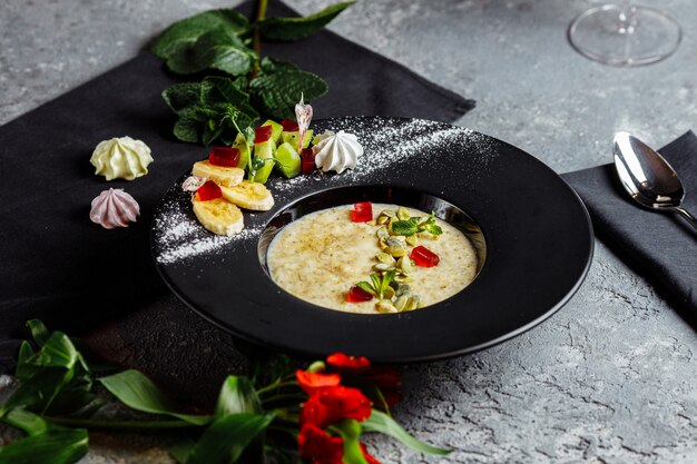 Avena con bayas, frutas y mermelada en la vista superior de la mesa verde azulado vintage en estilo plano laico. Desayuno caliente y saludable y comida dietética.