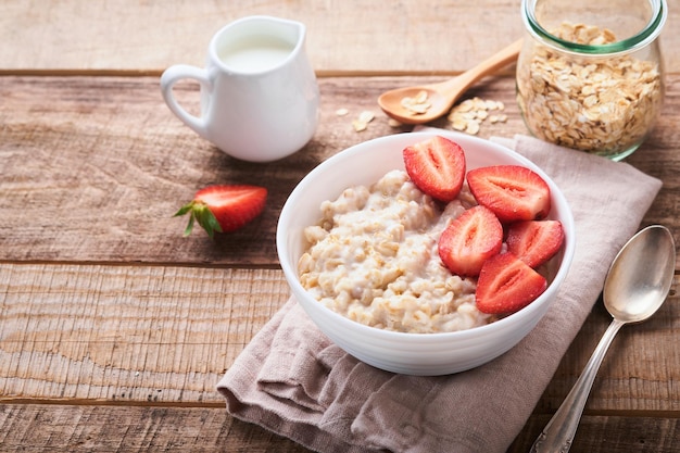 Avena Cuenco de gachas de avena con almendras de fresa y leche sobre fondo de mesa oscura de madera vieja Vista superior en estilo plano Ingredientes naturales Desayuno caliente y saludable y comida dietética