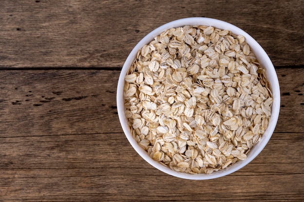 Foto avena enrollada en seco en un tazón sobre fondo de madera vista superior