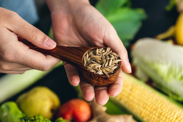 Avena entera en un primer plano de cuchara de madera sobre un fondo de verduras