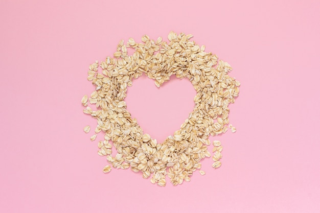 Avena en forma de corazón con espacio vacío para el texto sobre fondo rosa. Concepto de dieta