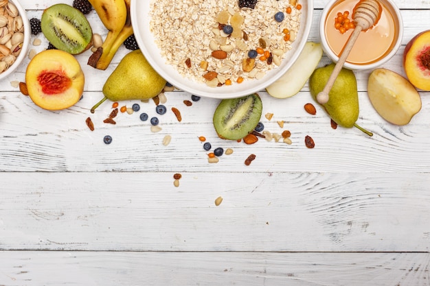 Avena con fruta y miel sobre una mesa de madera blanca