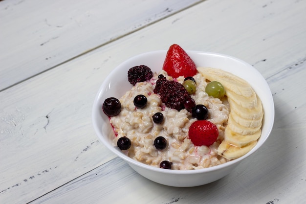 avena con frutas en un tazón blanco sobre una mesa de madera blanca