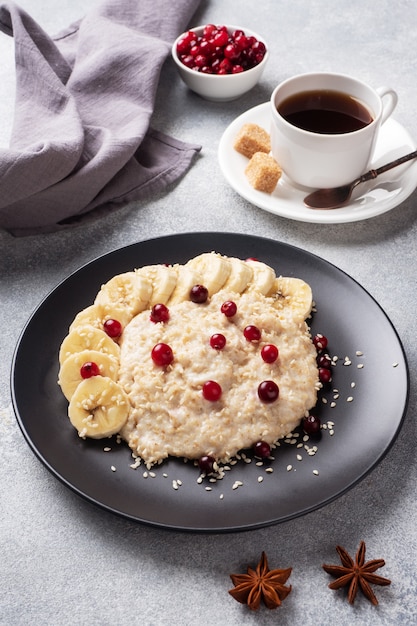 Avena con leche con arándanos rojos y semillas de sésamo. Una taza de café, desayuno saludable concepto.