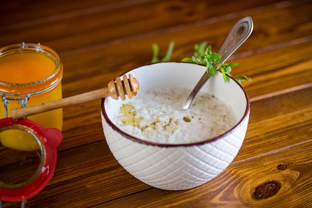 Foto avena de leche con miel para el desayuno en un tazón en una mesa de madera