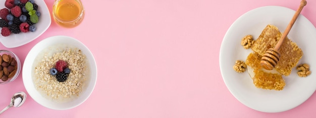 Avena con miel y bayas en el tazón blanco sobre fondo rosa Desayuno Vista superior Espacio de copia