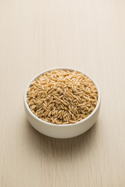 Avena en un pequeño cuenco blanco en una mesa de madera