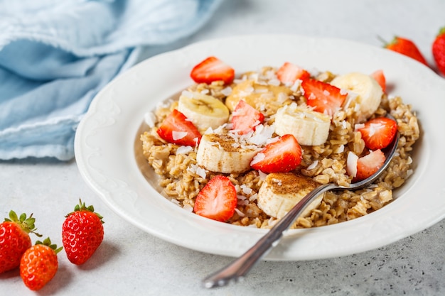 Avena con plátano, fresas y mantequilla de maní en plato blanco.