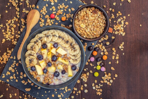 Avena con plátanos, arándanos y manzana en mesa de madera oscura