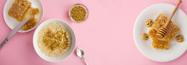 Avena con polen de abeja y miel en el tazón blanco sobre fondo rosa Desayuno Vista superior Copiar espacio