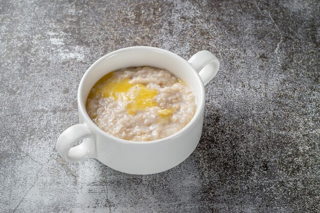 Avena en una taza blanca contra una mesa de piedra gris. Un desayuno saludable en un restaurante.