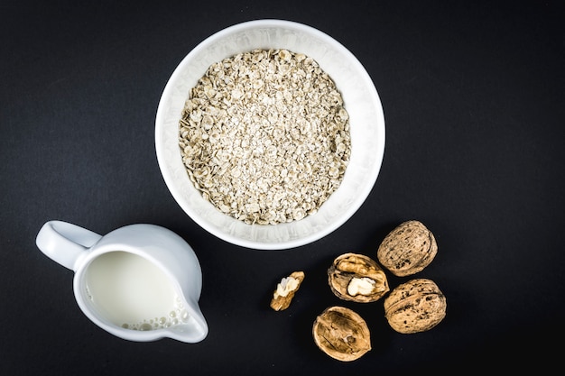 Avena en una taza y nueces aladas y leche. Receta de avena con nueces, ciruelas pasas, canela y azúcar.