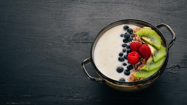 Avena con yogur y frutas y bayas Kiwi arándano frambuesa Sobre un fondo de madera Vista superior Espacio libre para texto