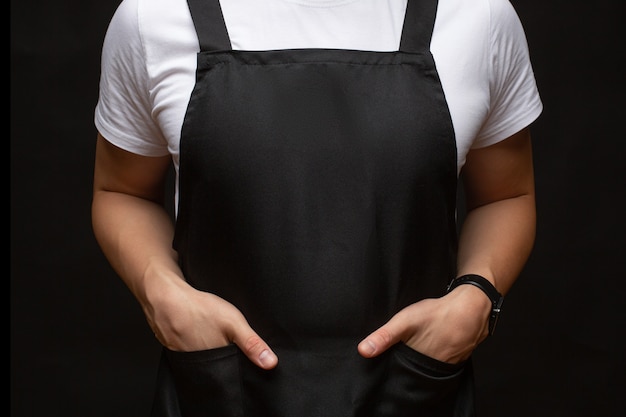 Avental preto em um close do homem. mãos nos bolsos. lugar para texto. cópia-espaço.