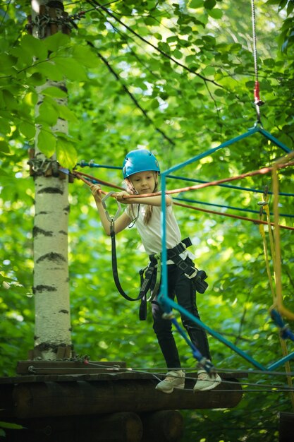 Aventura de cuerda extrema en el bosque una niña camina en el puente de cuerda